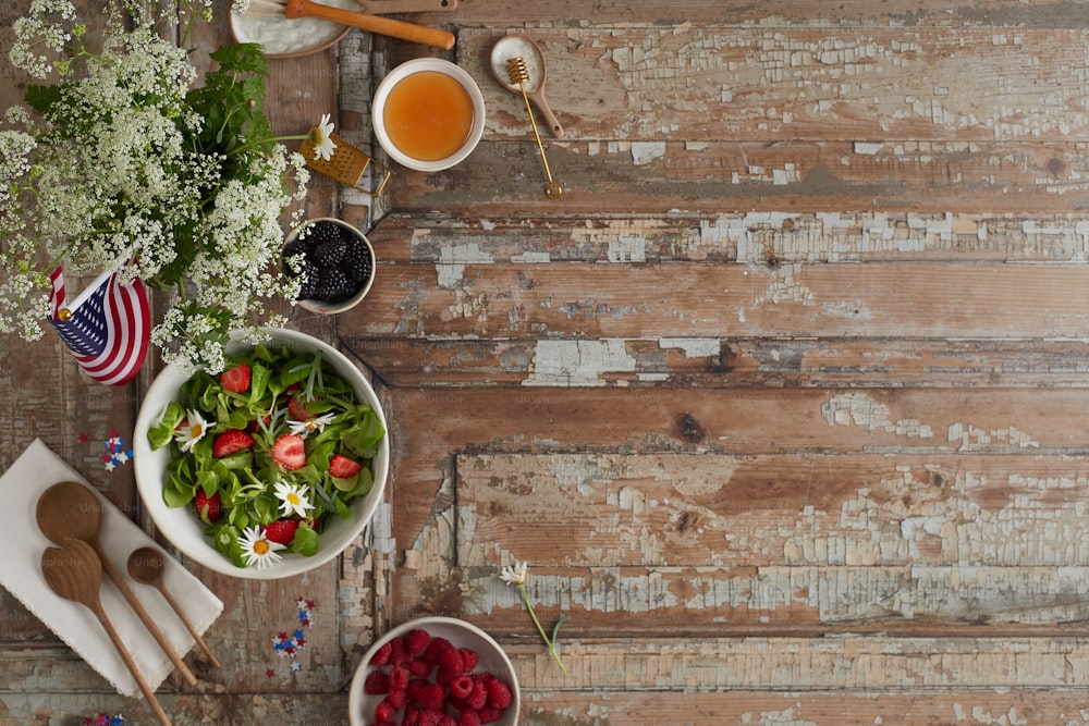 a wooden table topped with bowls of salad and fruit