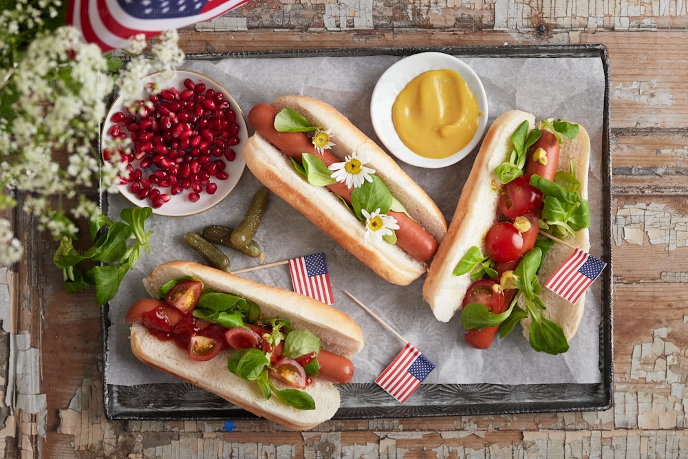 a tray with three hot dogs and a bowl of mustard