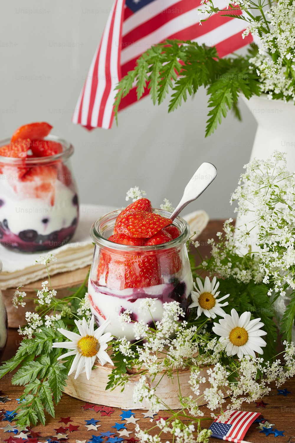 a bowl of strawberries and yogurt with a flag in the background