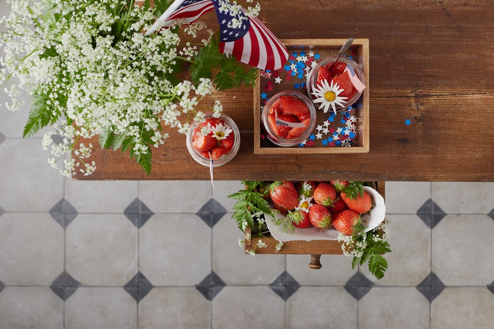 a wooden table topped with a bowl of strawberries