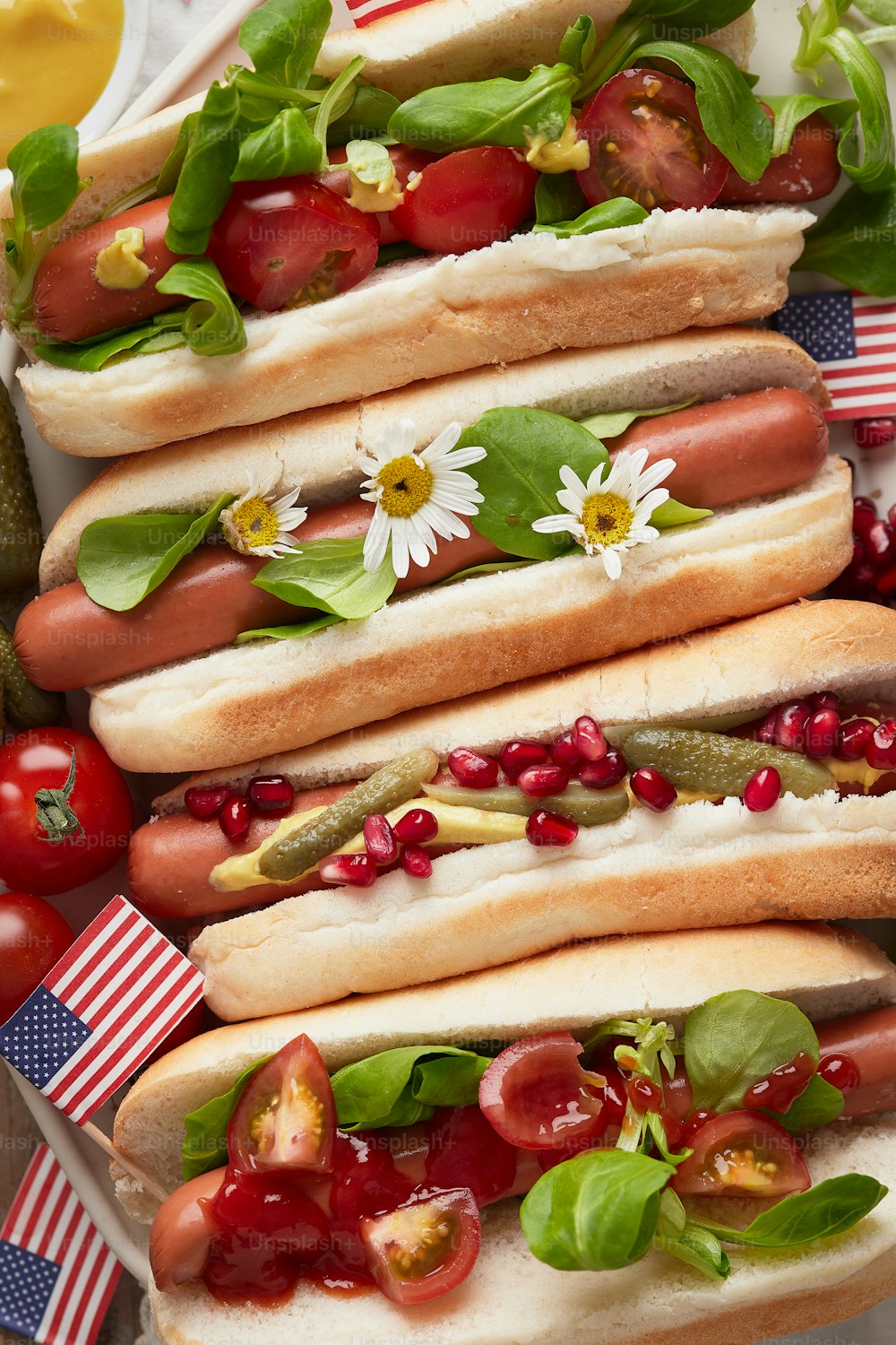 a plate of hot dogs with tomatoes, onions, and spinach