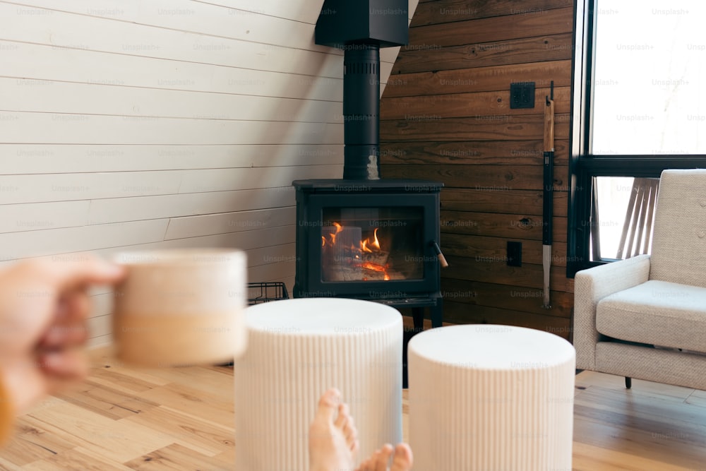 Una persona sosteniendo una taza de café frente a una chimenea