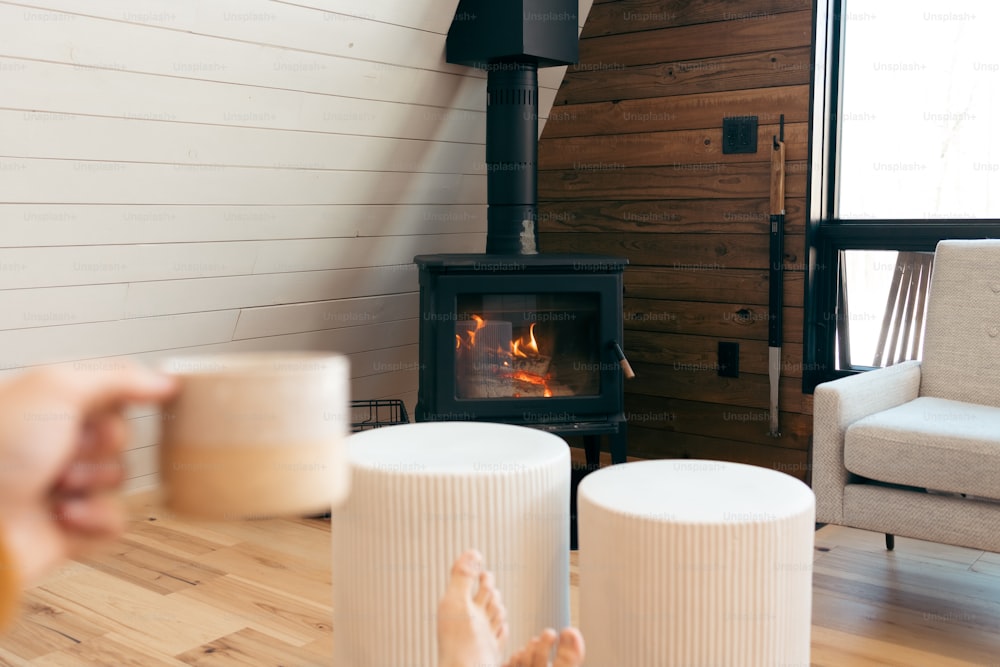 a person holding a coffee cup in front of a fireplace