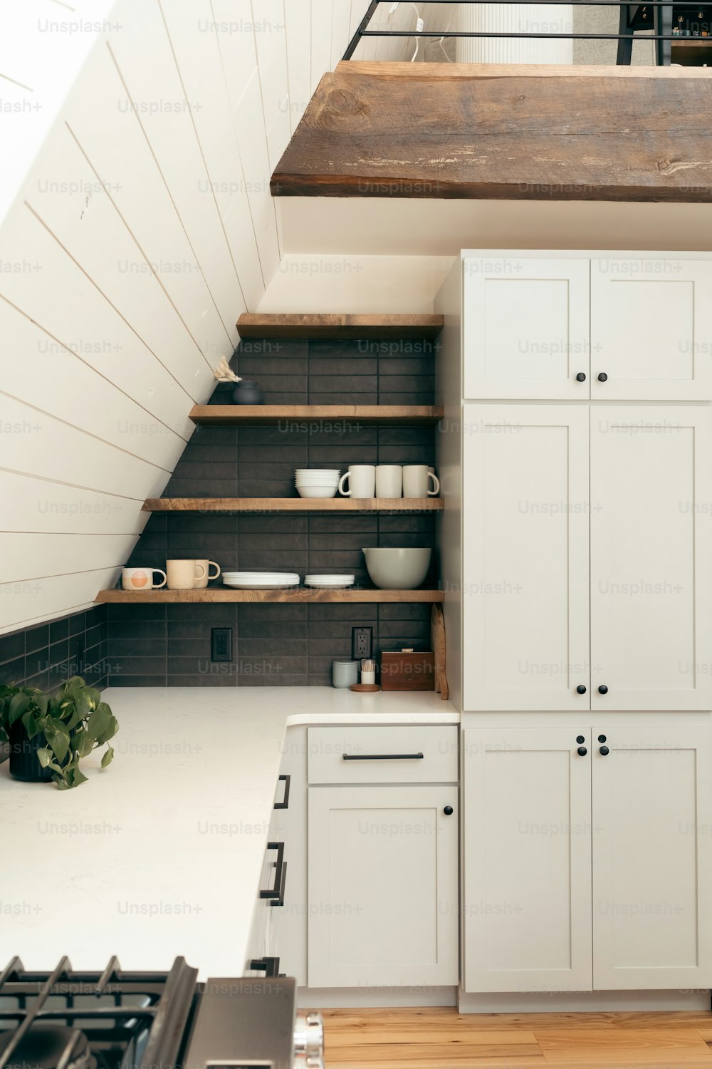 a kitchen with white cabinets and wooden shelves