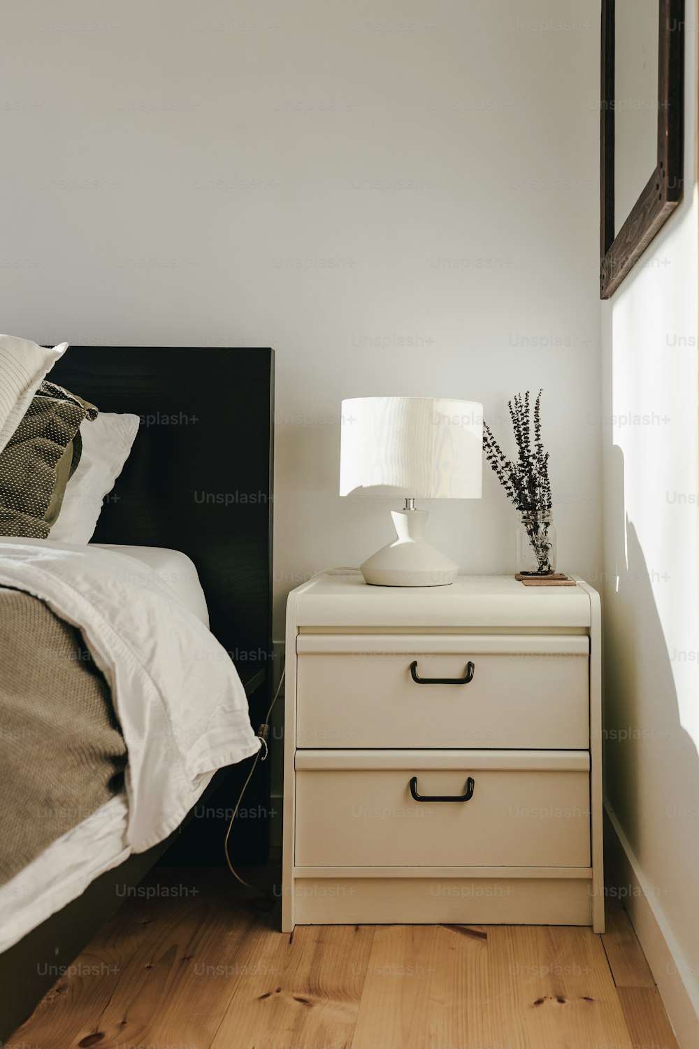 a bedroom with a bed and a nightstand with a lamp on top of it