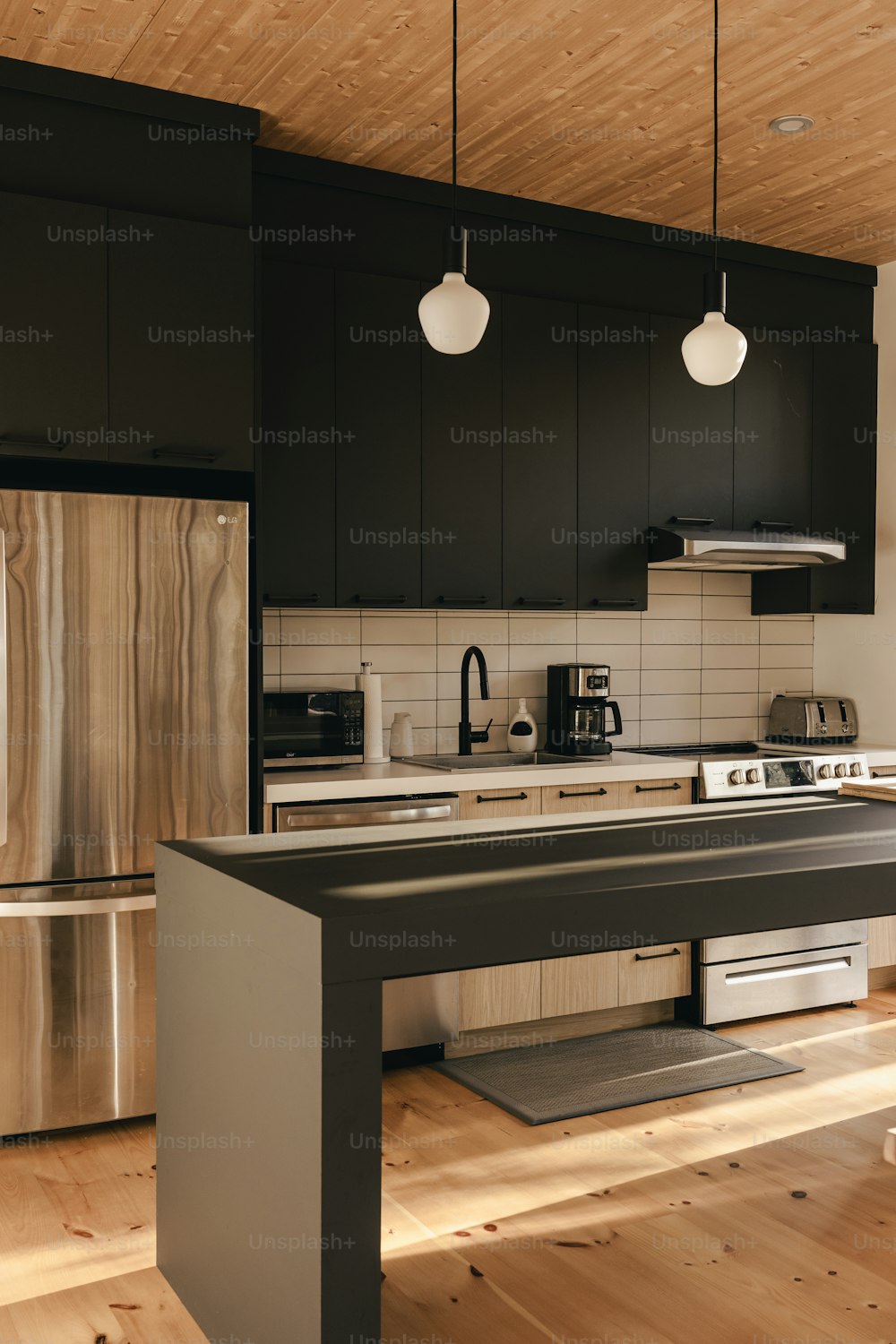 una cocina con gabinetes negros y electrodomésticos de acero inoxidable