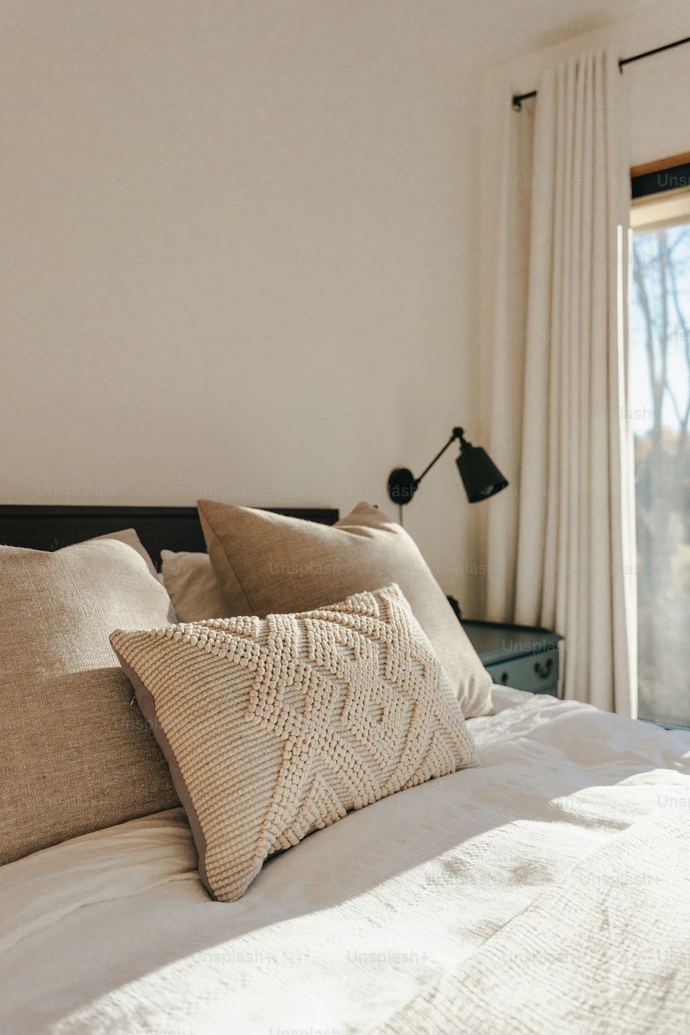 a bed with a white comforter and pillows