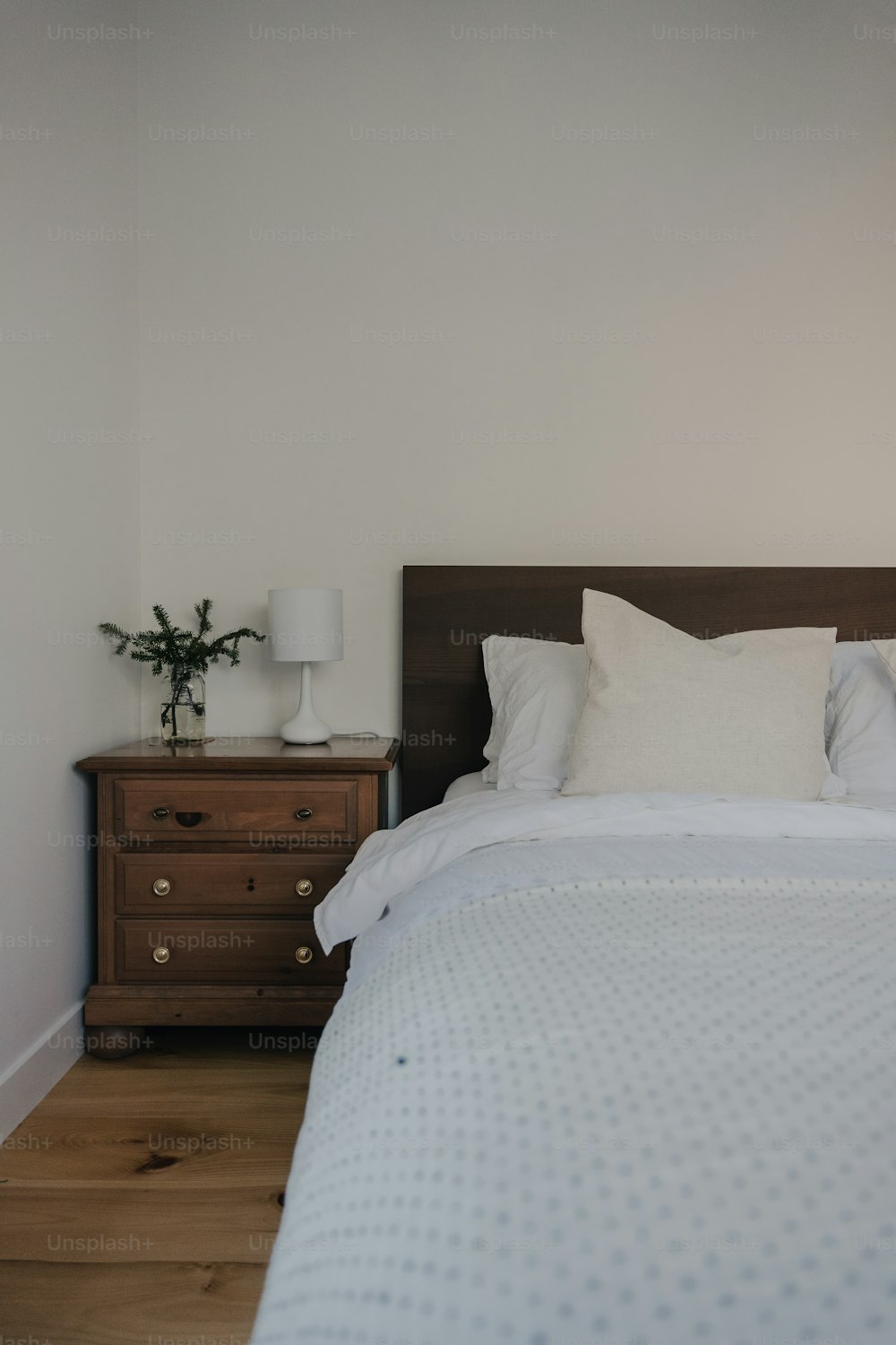 a bed with white sheets and pillows in a room