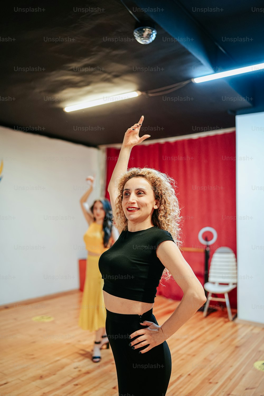 a woman standing on a wooden floor with her arms in the air