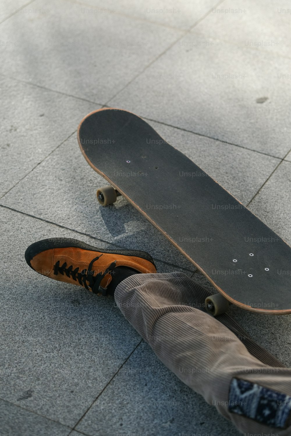 una persona sdraiata a terra accanto a uno skateboard