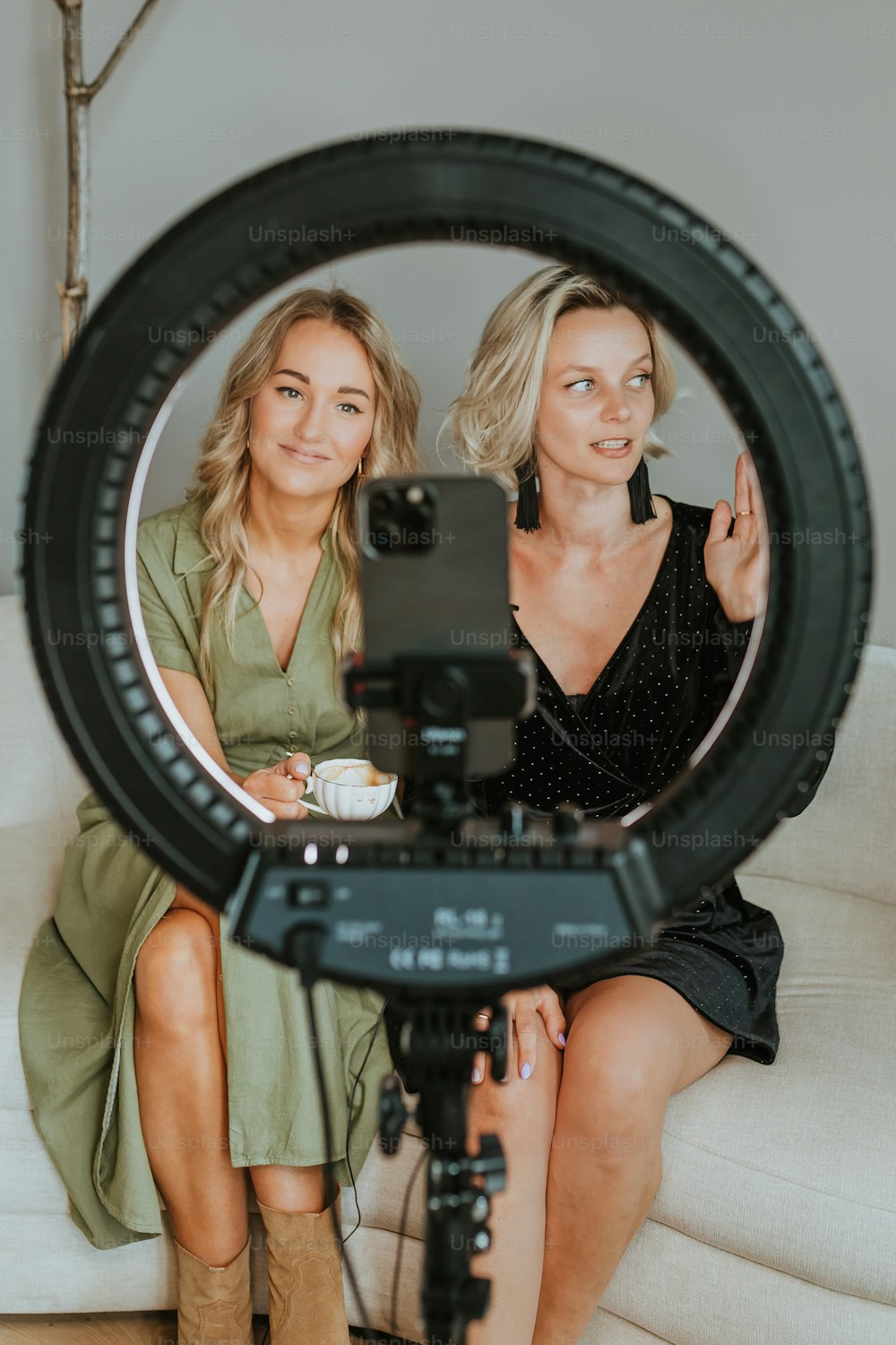 two women sitting on a couch with a camera in front of them