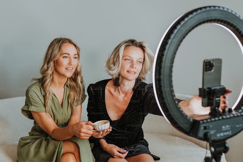 two women sitting on a couch with a camera