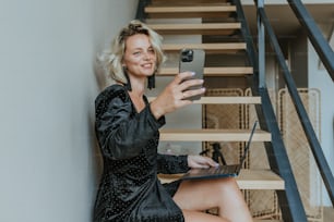 a woman in a black dress sitting on a stair case
