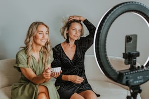 two women sitting on a couch in front of a camera