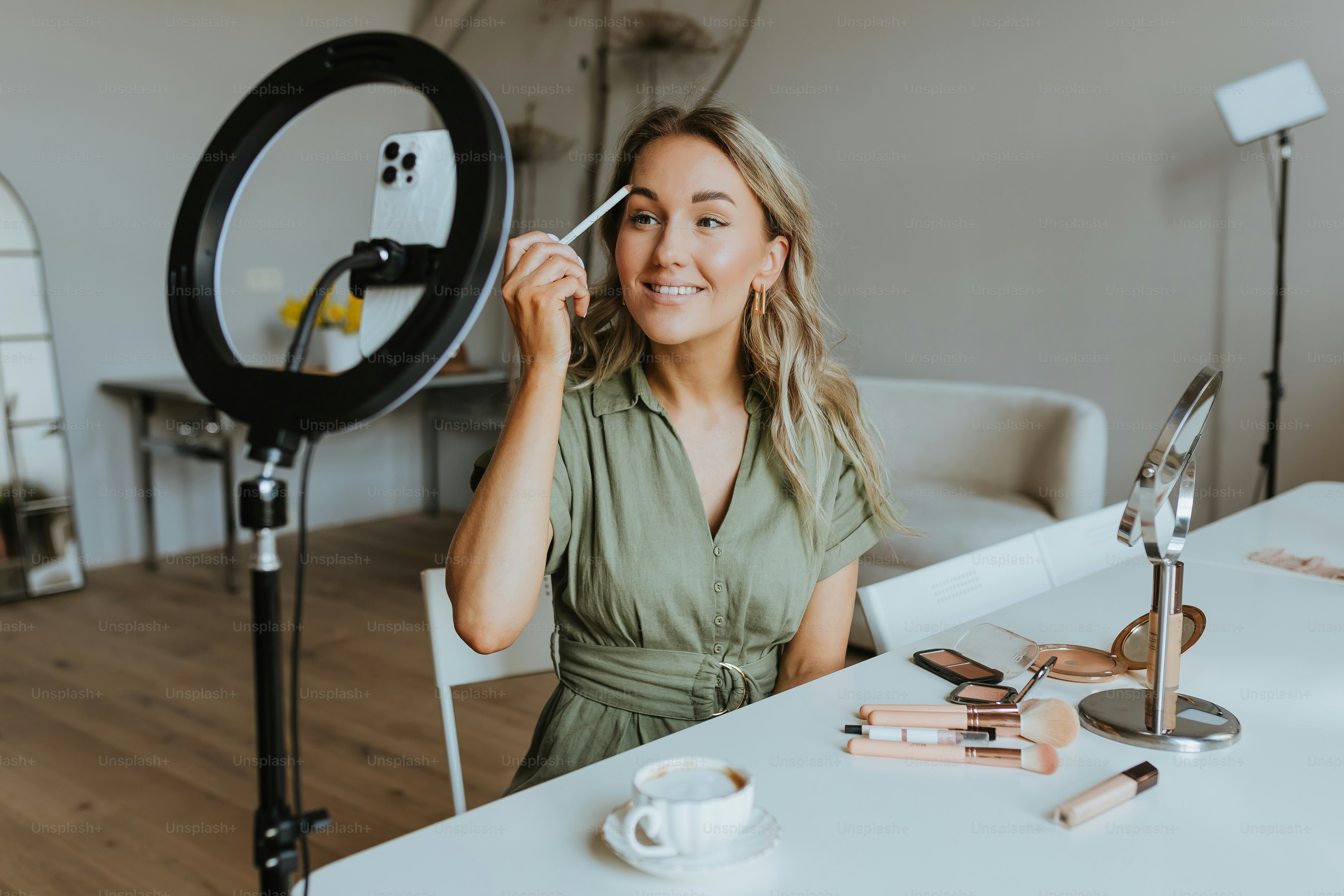 a woman sitting in front of a camera holding a phone