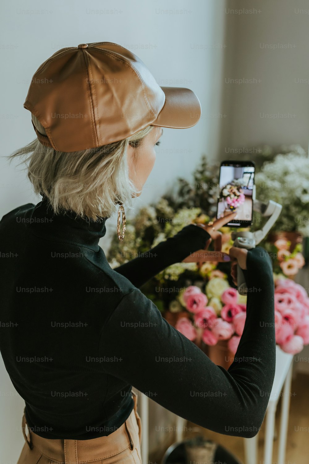 a woman taking a picture of flowers with her cell phone