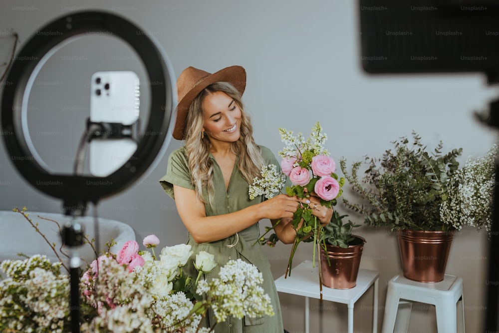 a woman in a hat is arranging flowers