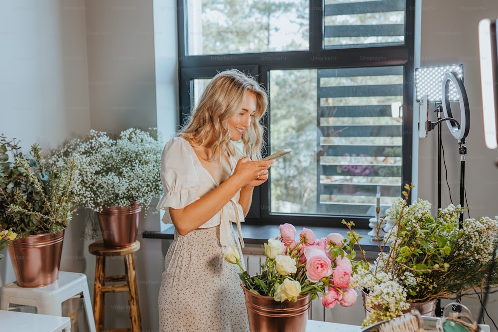 a woman standing in front of a window looking at her cell phone