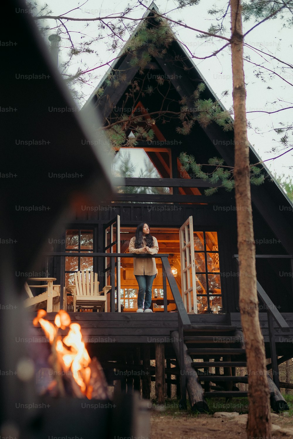 uma mulher em pé em uma varanda ao lado de uma fogueira