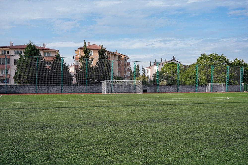 a soccer field with a soccer goal and buildings in the background