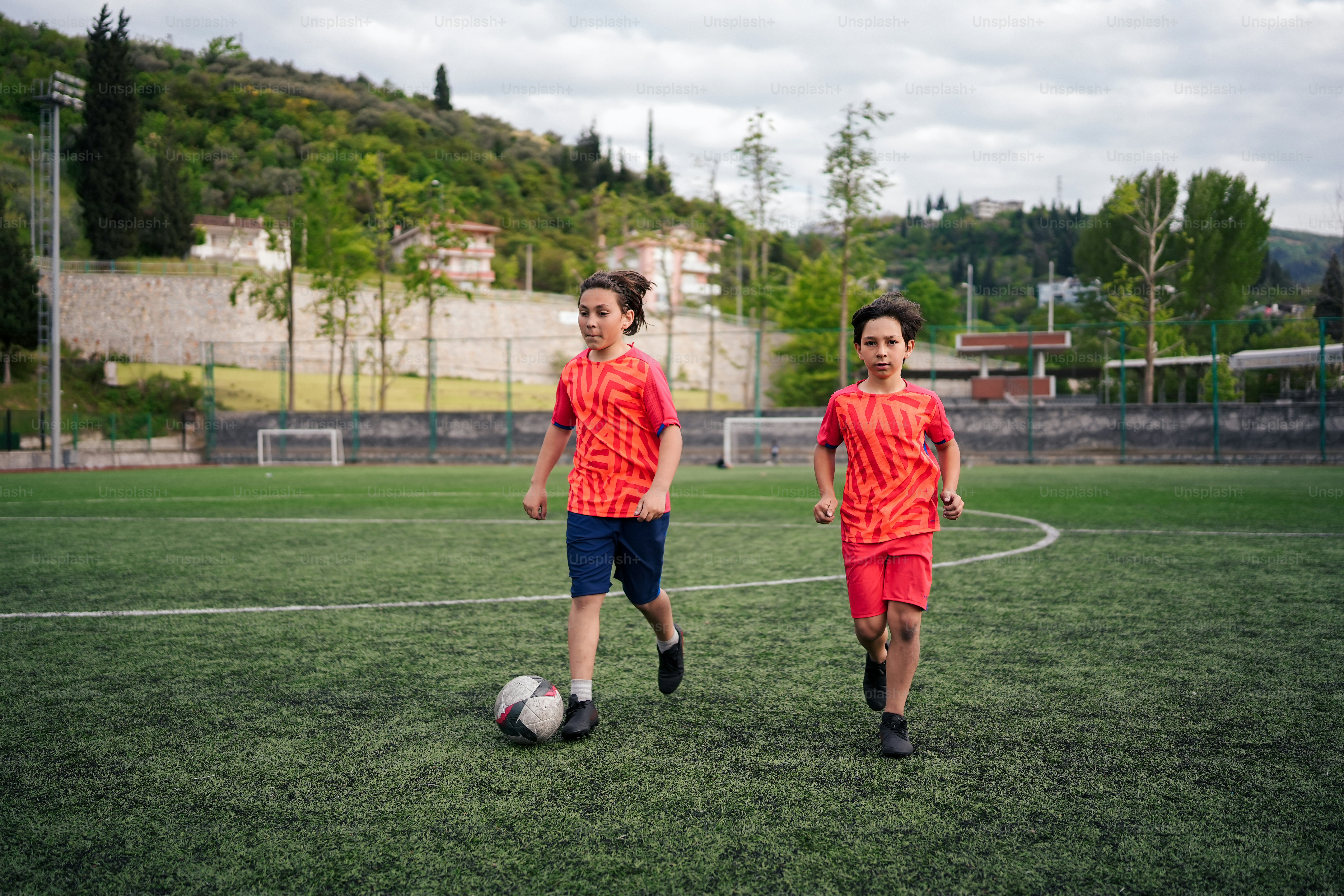 Un par de mujeres jóvenes de pie en la parte superior de un campo de fútbol