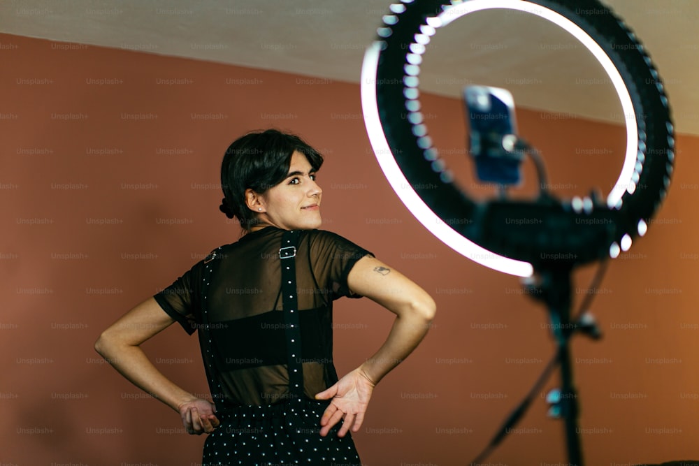 Una mujer parada frente a una cámara con las manos en las caderas