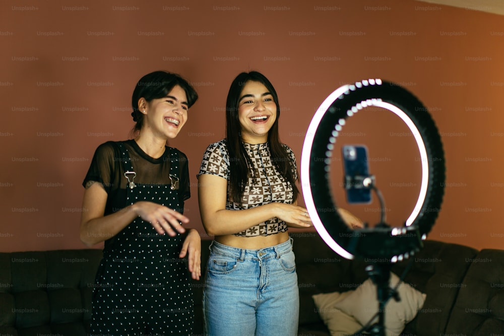 two women standing next to each other in front of a camera