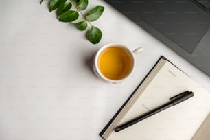 uma xícara de chá ao lado de um caderno e uma caneta