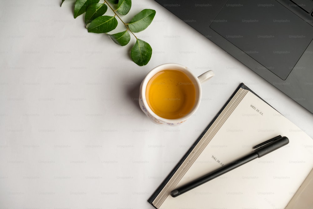 a cup of tea next to a notebook and a pen