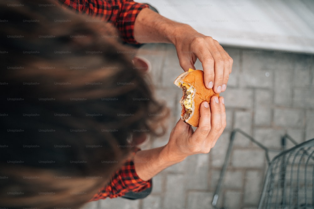une personne tenant un sandwich à moitié mangé dans sa main