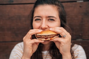a woman holding a hamburger in front of her face