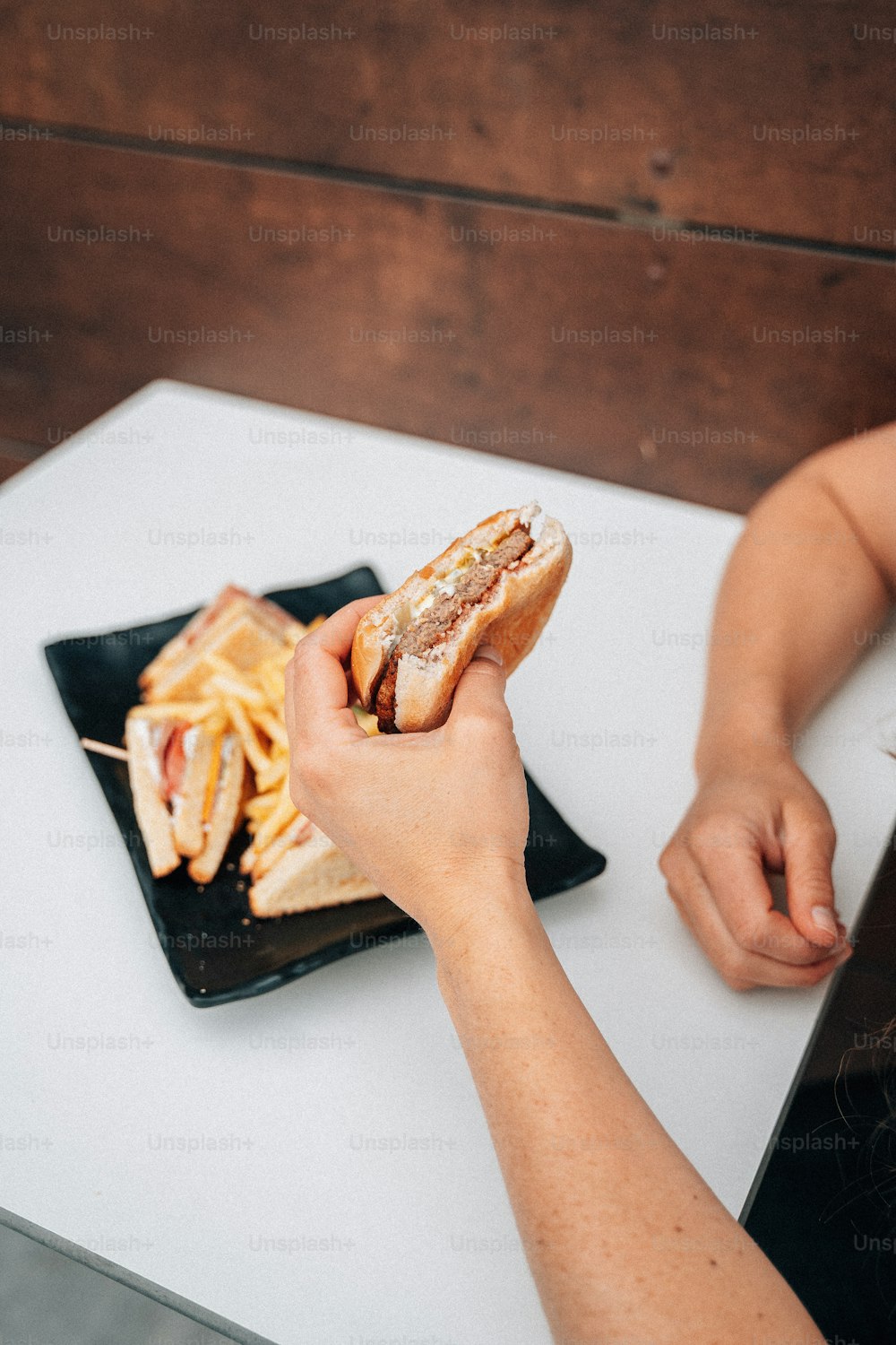 a person holding a hot dog on a black plate
