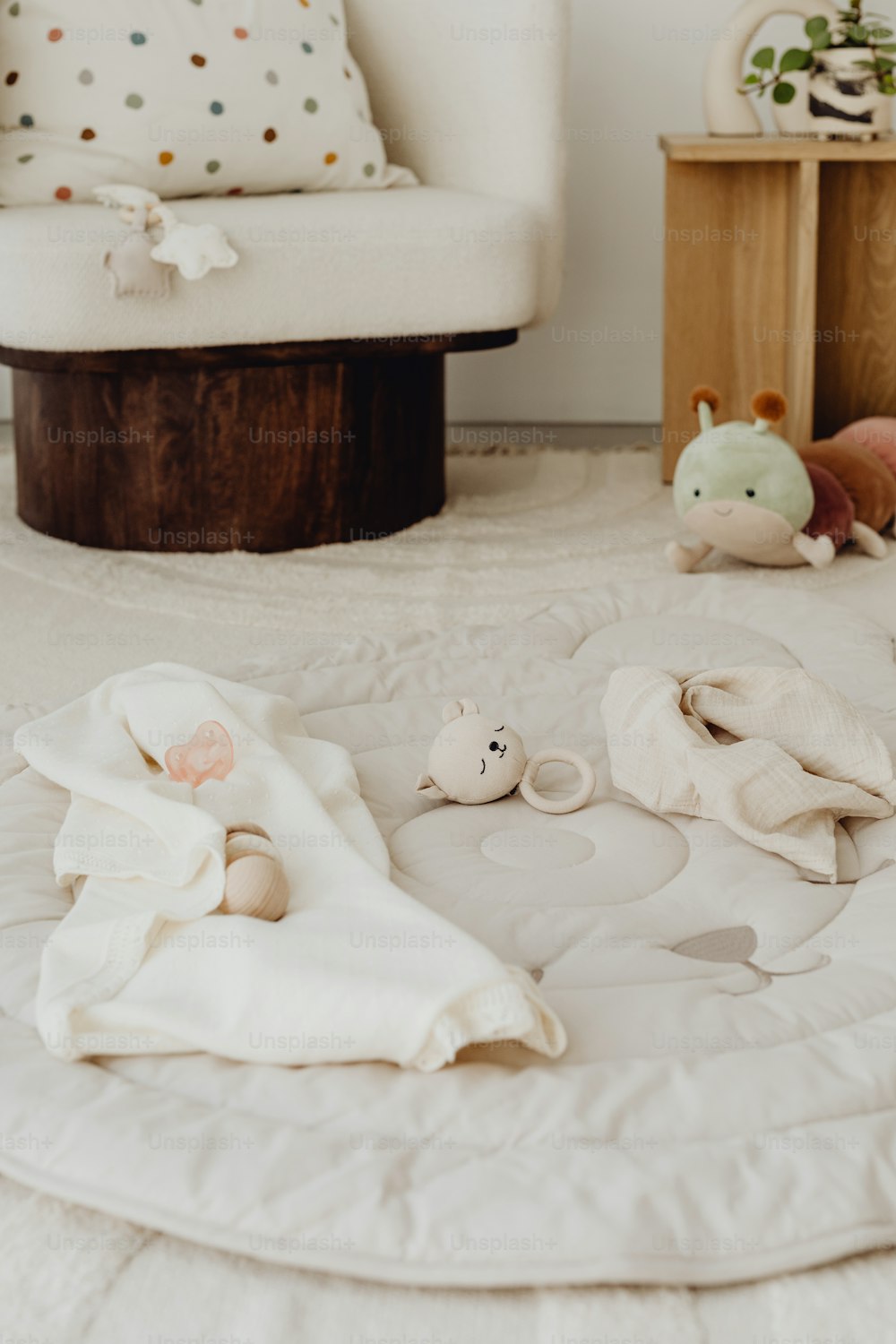 a baby's room with a white chair and stuffed animals on the floor