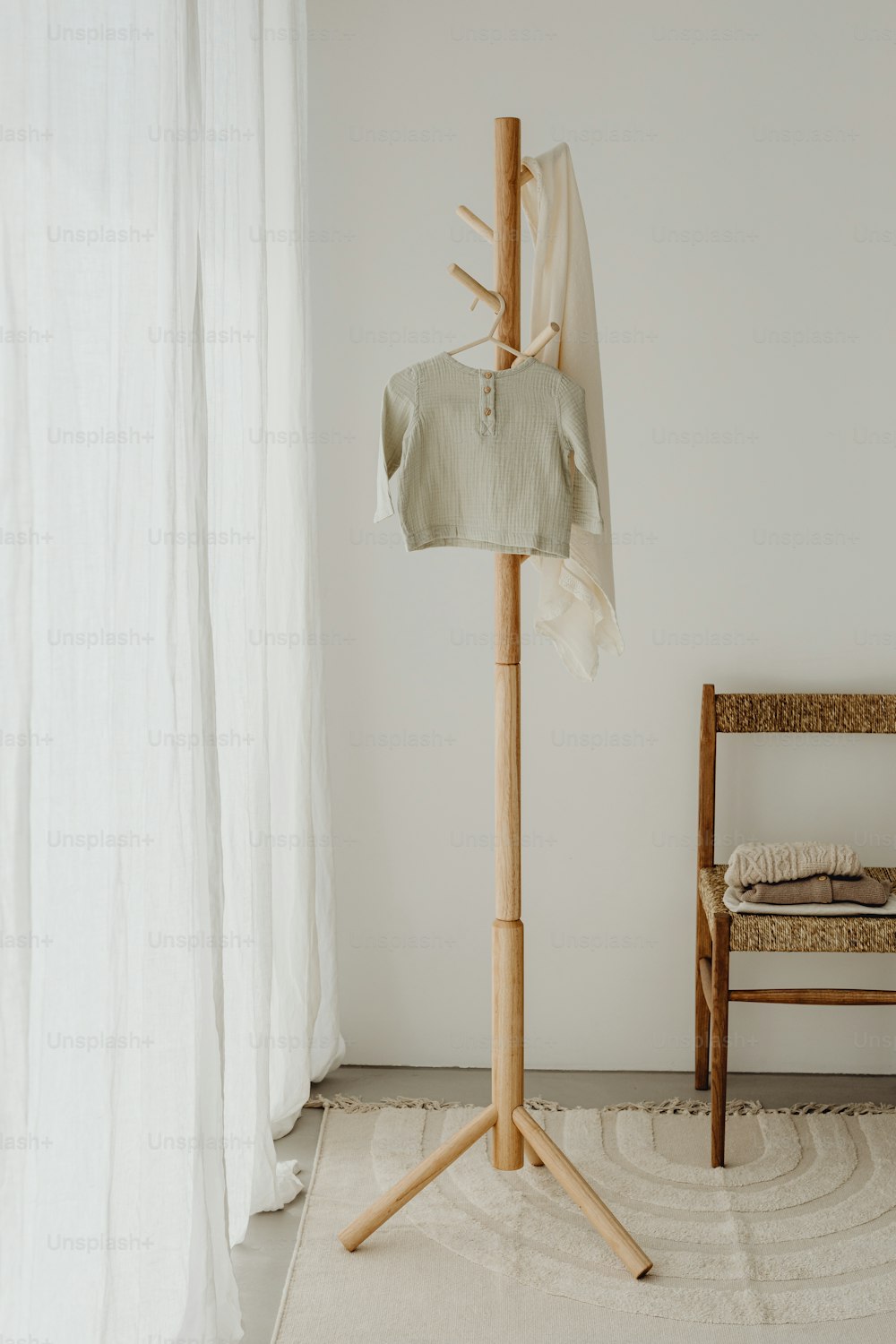 a wooden chair sitting next to a white curtain
