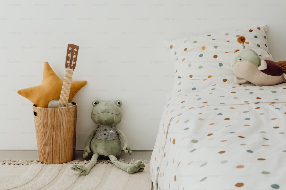 a stuffed frog sitting on the floor next to a bed