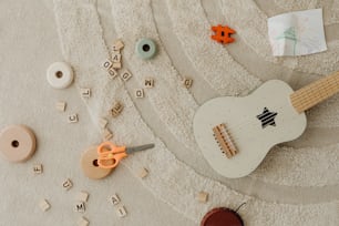 a white guitar sitting on top of a carpet next to a pair of scissors