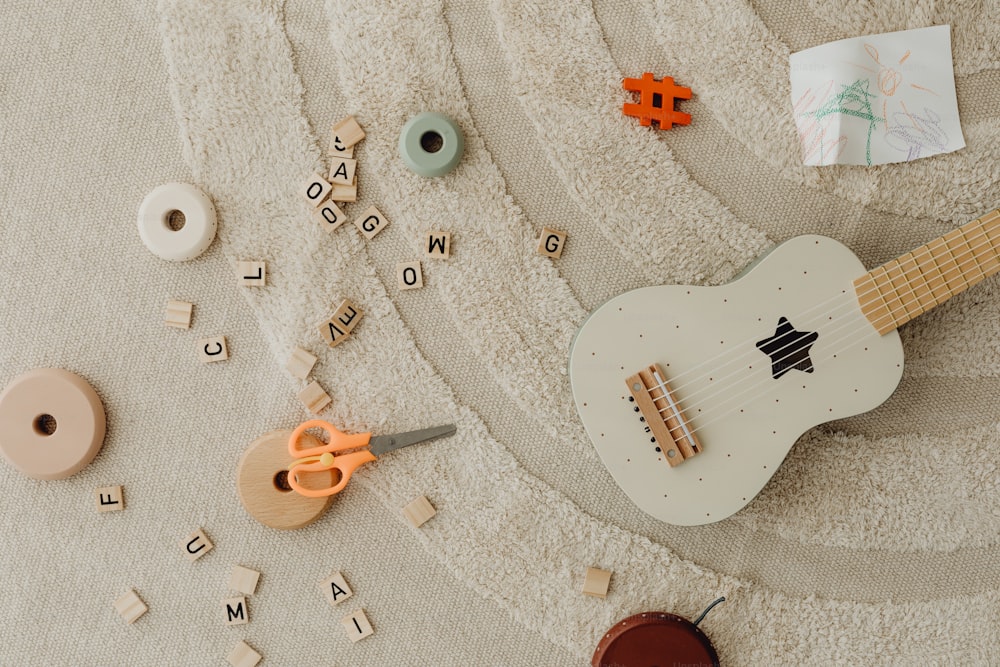 Una guitarra blanca sentada encima de una alfombra junto a un par de tijeras