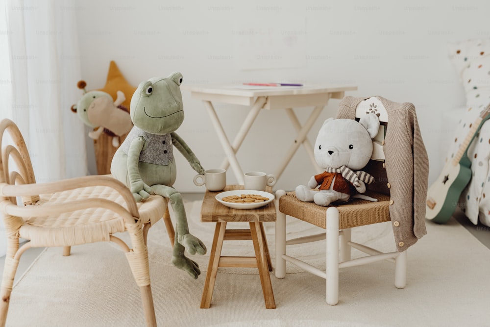 two stuffed animals sitting on chairs in a child's room