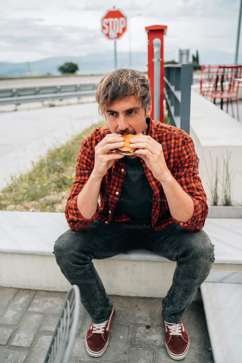 ein mann, der auf einem vorsprung sitzt und einen donut isst