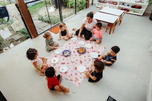 a group of children sitting around a table eating cake