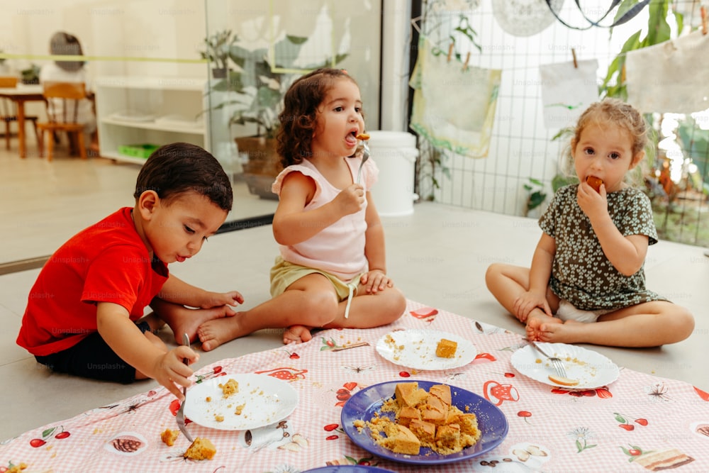 바닥에 앉아 음식을 먹는 세 아이