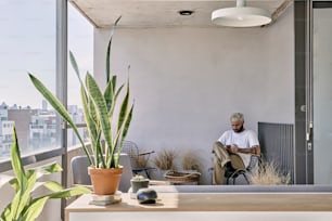 Un uomo seduto su un divano accanto a una pianta in vaso
