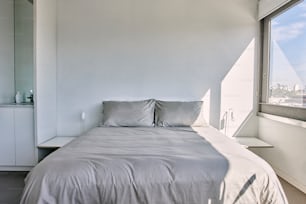 uma cama sentada ao lado de uma janela em um quarto