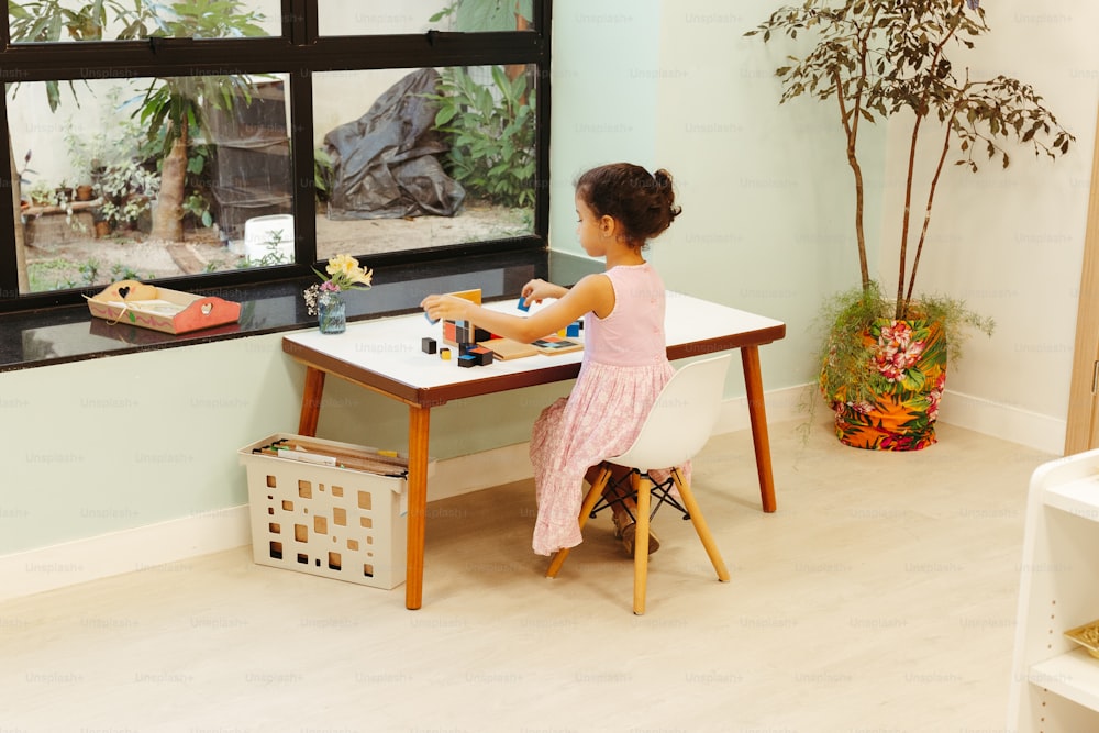 a little girl sitting at a table playing with a toy
