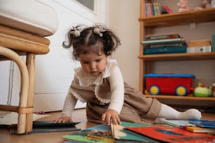 a little girl is playing with books on the floor
