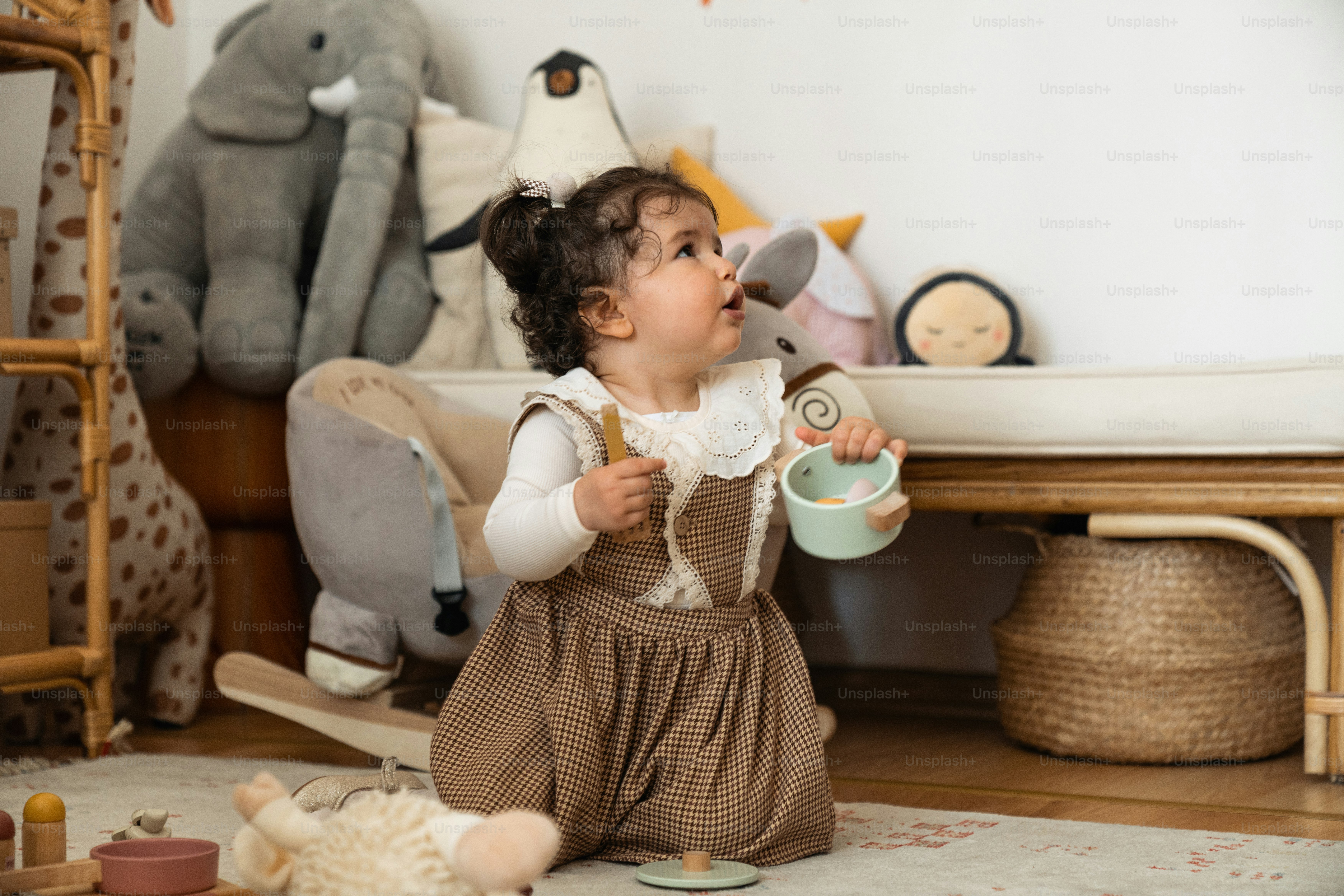 a little girl sitting on the floor drinking from a cup