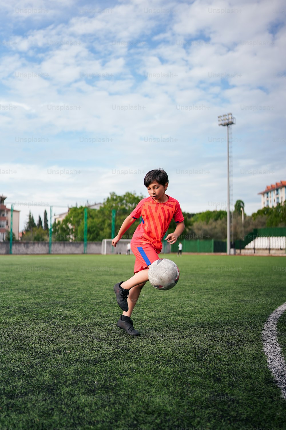 ein kleiner Junge, der einen Fußball auf einem Feld kickt