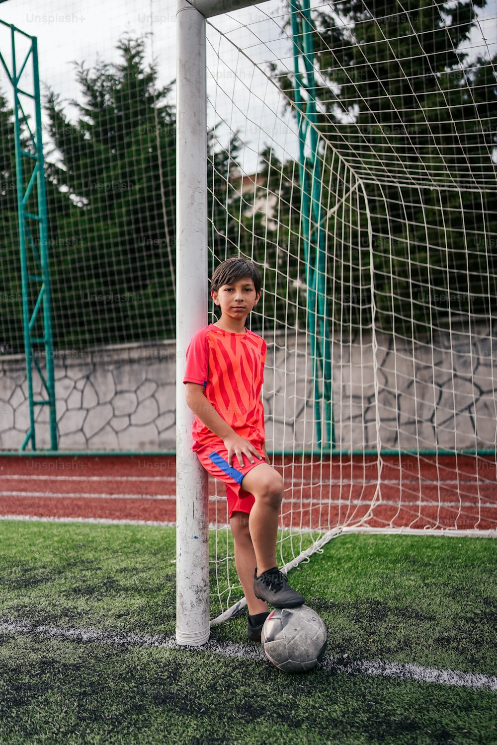 um menino em pé ao lado de uma bola de futebol