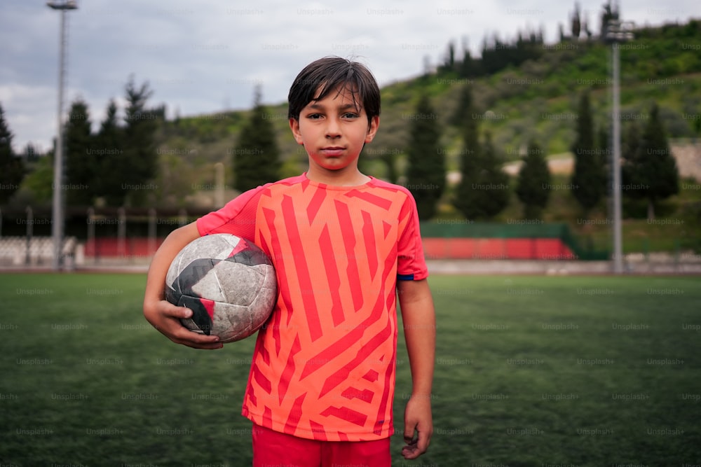 um menino segurando uma bola de futebol em um campo