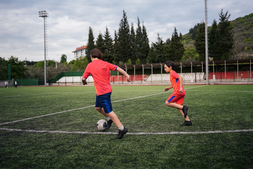 two young boys playing soccer on a soccer field